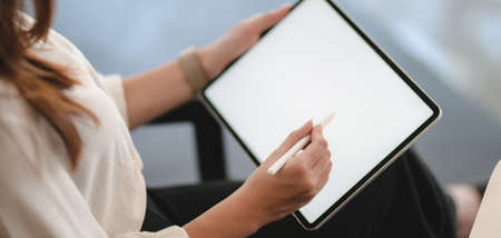 Cropped shot of young businesswoman working on her project while using blank screen tablet の写真素材