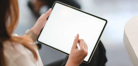 Cropped shot of young businesswoman using blank screen tablet in modern office room の写真素材