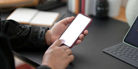Cropped shot of young businessman using blank screen smartphone in modern office room 