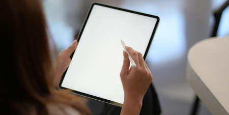 Cropped shot of young businesswoman working with blank screen laptop computer in office room の写真素材