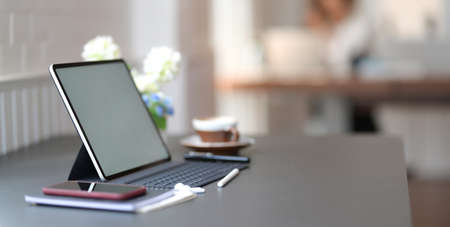 Close-up view of dark stylish workplace with blank screen digital tablet and office supplies on...