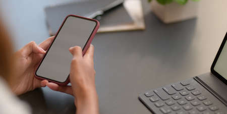 Cropped shot young businesswoman holding blank screen smartphone while working on her project の写真素材