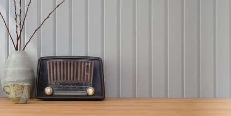 Close-up view of vintage workplace with vintage radio and decorations on wooden table and white plank wall backgroundの写真素材