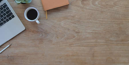 Overhead shot of comfortable workplace with laptop computer and office supplies on wooden table