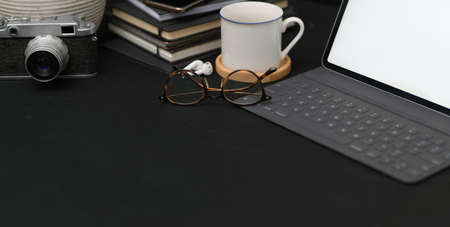 Close-up view of dark trendy workplace with mock up tablet and office supplies with copy space 