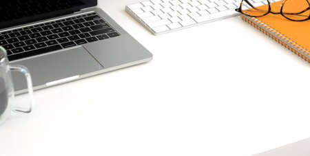 Cropped shot of trendy workplace with laptop computer na office supplies on white table background 