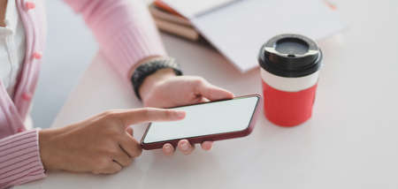 Cropped shot of young businessman using blank screen smartphone in modern office roomの写真素材
