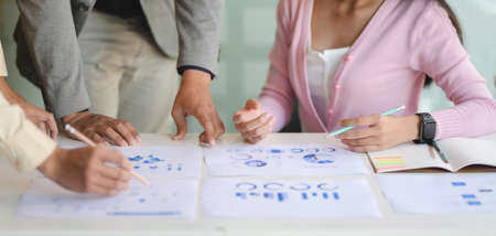 Cropped shot of young professional business team discussing the project with document and charts in...