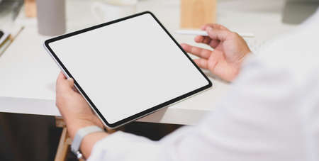 Cropped shot of young businessman working on his project while using blank screen tablet