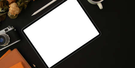 Top view of dark stylish workplace with blank screen tablet and office supplies on black table backgroundの写真素材