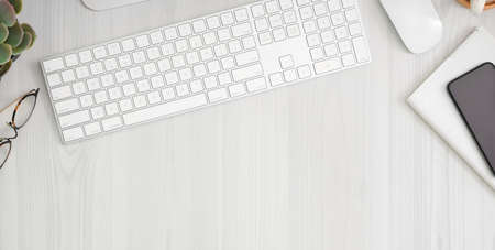 Cropped shot of comfortable workplace with smartphone, office supplies and copy space on white wooden table の写真素材