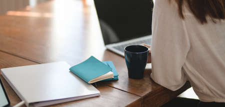 Cropped shot of businesswoman working on her project while drinking a cup of coffee in office roomの写真素材