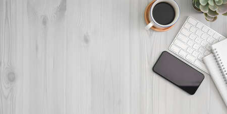 Cropped shot of comfortable workplace with smartphone, office supplies and copy space on white wooden table の写真素材
