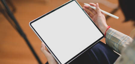 Cropped shot of young businesswoman working on her project while using blank screen digital tablet