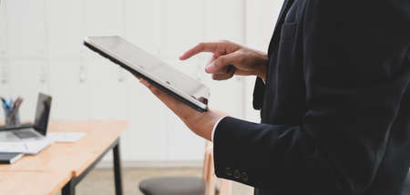 Cropped shot of young businessman working on his project while using tablet in office room 