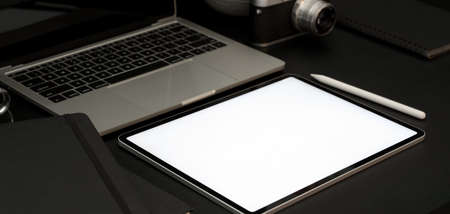 Close-up view of dark luxury workplace with open blank screen laptop computer and office supplies 