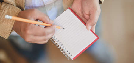 Cropped shot of young businessman working on his project while writing the ideas on notebook