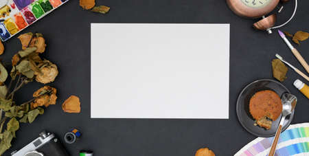 Top view of vintage artist creative studio with sketch paper and painting tools on black table...