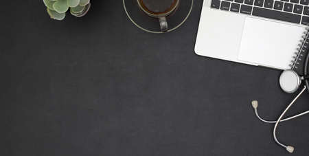 Overhead shot of dark trendy workplace with laptop computer and office supplies on black table...