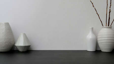 Close up view of modern workspace with   ceramic vase on black desk with white wall backgroundの写真素材
