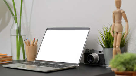 Close up view of modern workspace with mock up laptop, wooden figure, books and decorations on black...