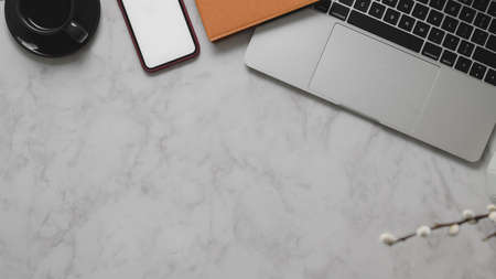 Top view of modern workspace with copy space, laptop, blank screen smartphone and office supplies on...