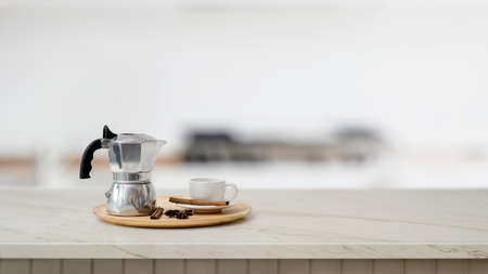 Close up view of mock pot and coffee cup on marble desk with blurred kitchen background の写真素材