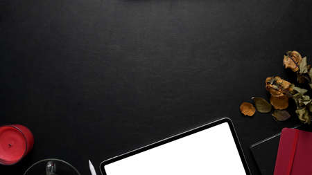 Top view of luxury workspace with blank screen tablet, office supplies and decorations on black...