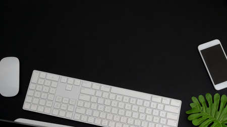Top view of dark modern workspace with copy space, computer keyboard and smartphone on black table background  の写真素材
