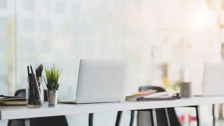 Cropped shot of modern workplace with laptop, stationery and office supplies on white wooden table...