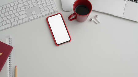 Cropped shot of modern office room with blank screen smartphone and office supplies on white tableの写真素材