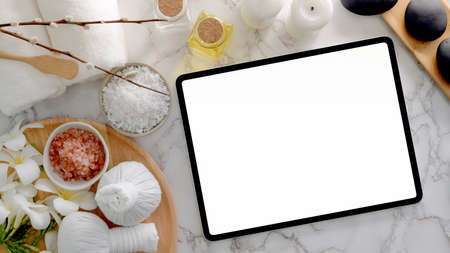 Top view of Beauty spa treatment and relax concept with blank screen tablet,  spa salt, hot stone...