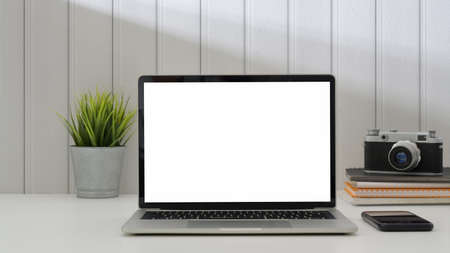 Close up view of trendy workplace with mock up laptop , camera, smartphone  and decoration on white...