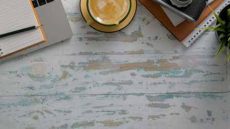 Top view of rustic workplace with laptop, camera, office supplies, coffee cup  and copy space on...