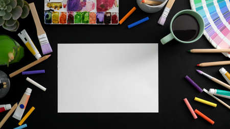 Top view of professional artist workspace with sketch paper, painting tools and coffee cup on black table の写真素材