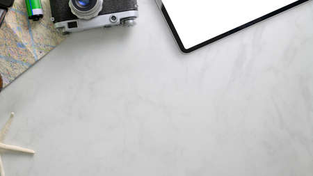 Overhead shot of vacation items with copy space, camera, digital tablet and  map on marble desk...