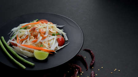 Cropped shot of papaya salad or Somtum on black plate and copy space with dark table backgroundの写真素材