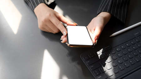 Cropped shot of businesswomen using  blank screen smartphone with digital tablet in modern dark...