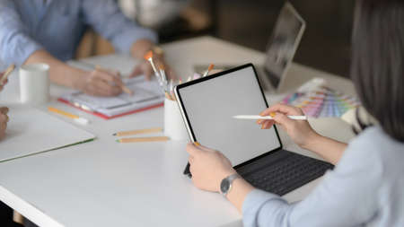 Cropped shot of female app developer drawing on mock up tablet while discussing with her UI...