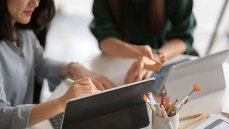 Close up view of young professional designer team briefing on their project with digital tablet in...