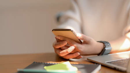 Close-up view of young girl using her smartphone while sitting in co-working spaceの写真素材