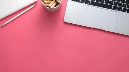 Top view of stylish artist workspace with laptop, stationery and copy space on pink table backgroundの写真素材