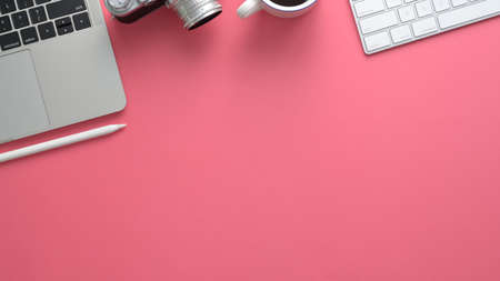 Top view of stylish photographer workspace with computer, laptop, camera and copy space on pink table backgroundの写真素材