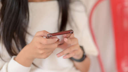 Close-up view of young girl using her smartphone while sitting in co-working space の写真素材