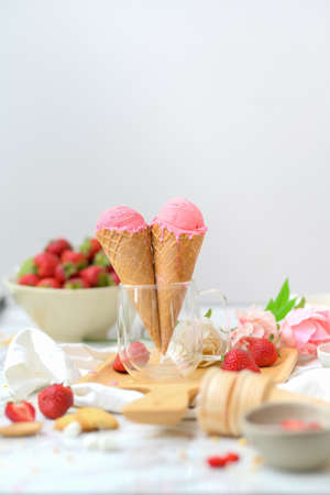 Cropped shot of summer dessert with strawberry flavour ice-cream cones and topping on marble desk の写真素材