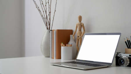 Cropped shot of minimal photographer workplace with blank screen laptop, camera  and decorations on white desk の写真素材