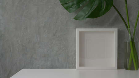 Close up view of modern workspace with  copy space, mock up frame and vase on white table with grey loft wallの写真素材