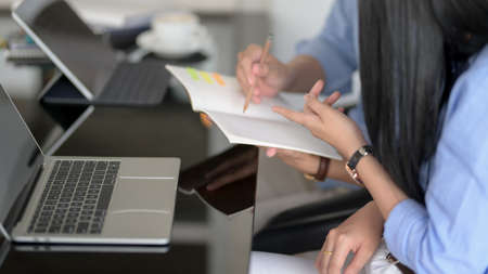Side view of  two businesspeople discussing on their work while looking on notebook