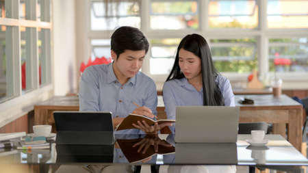 Close up view of two businesspeople concentrating  on their work while sitting in simple co-working...