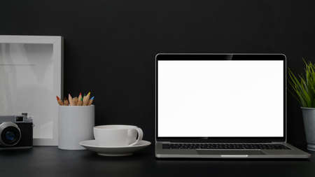 Close up view of trendy photographer workplace with mock up laptop, frame, camera and decorations on...
